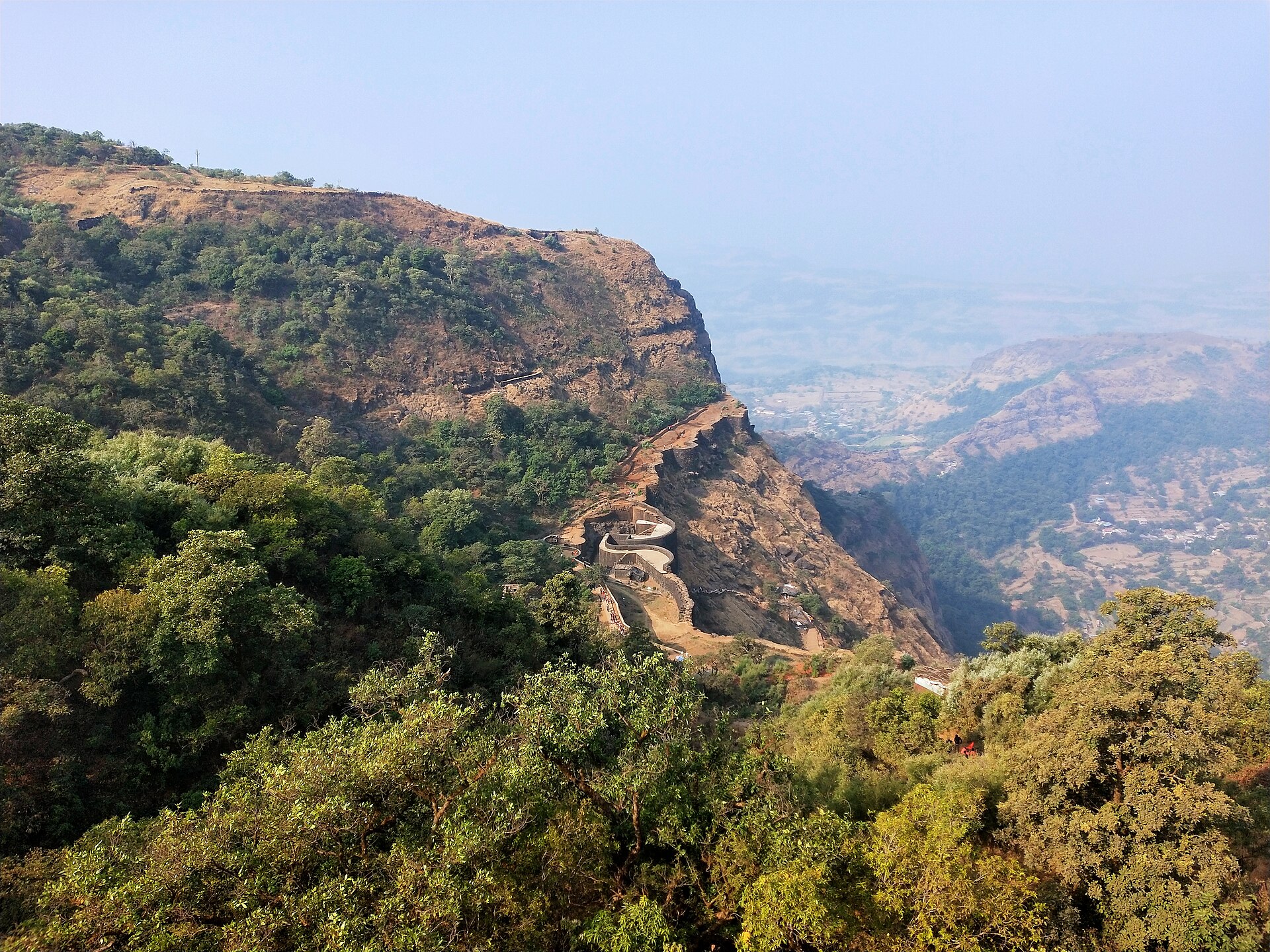 The walls and main gate of Raigad fort winding along a cliff in the Sahyadri hills
